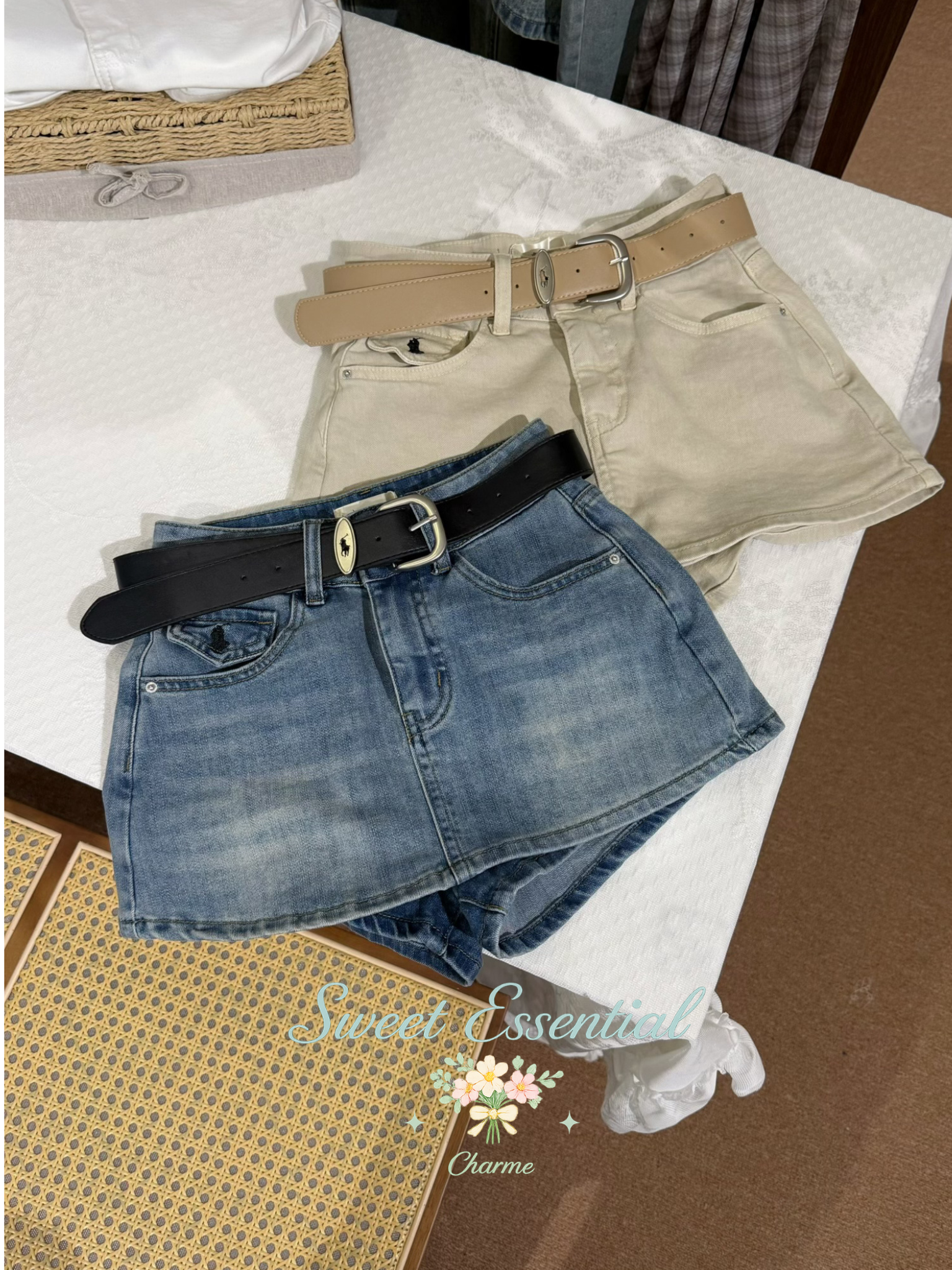 Pair of denim shorts with a black belt and beige shorts with a tan belt on a white surface.