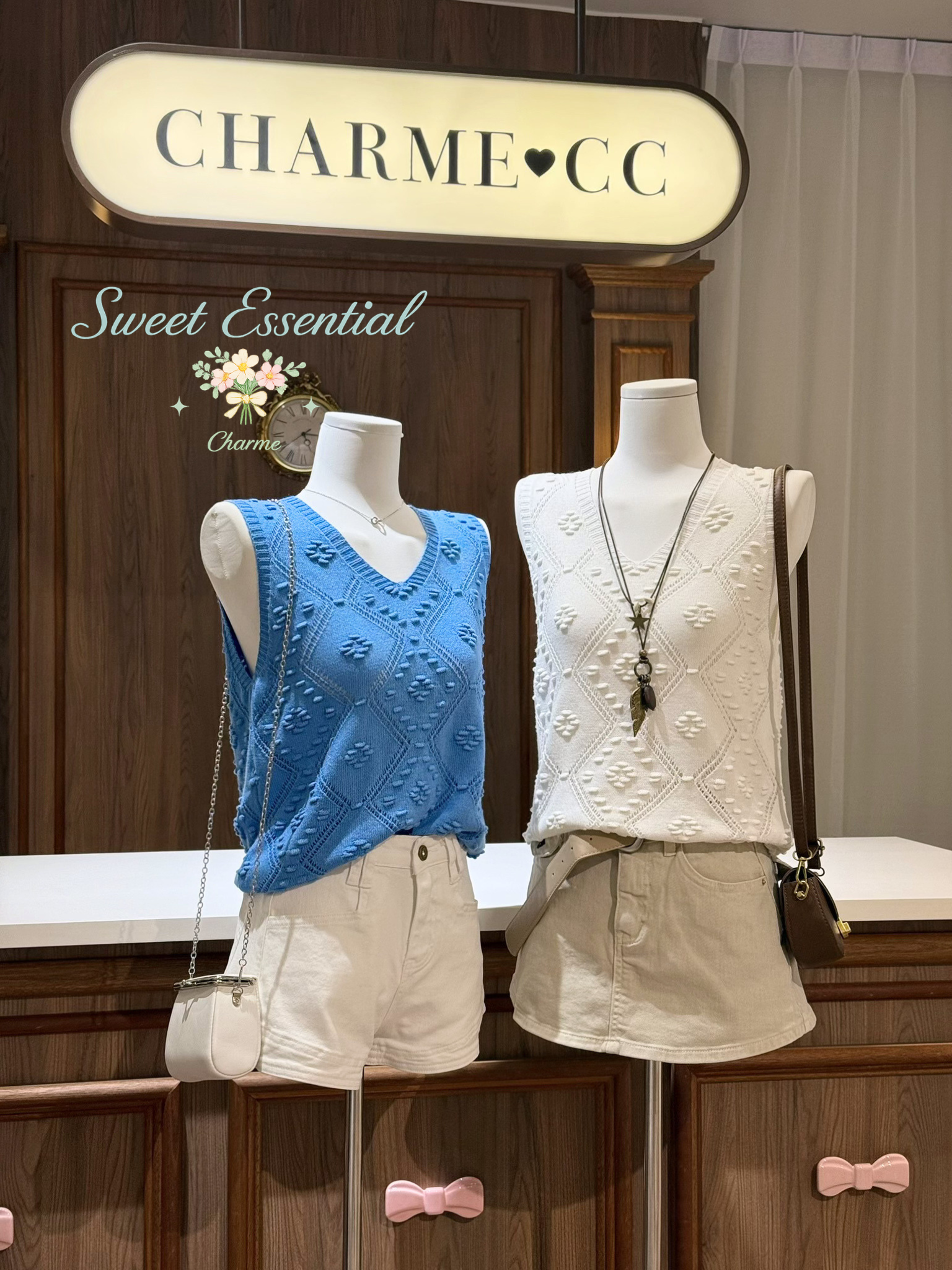 Two mannequins wearing blue and white tops with beige shorts, standing under a 'CHARME CC' sign.