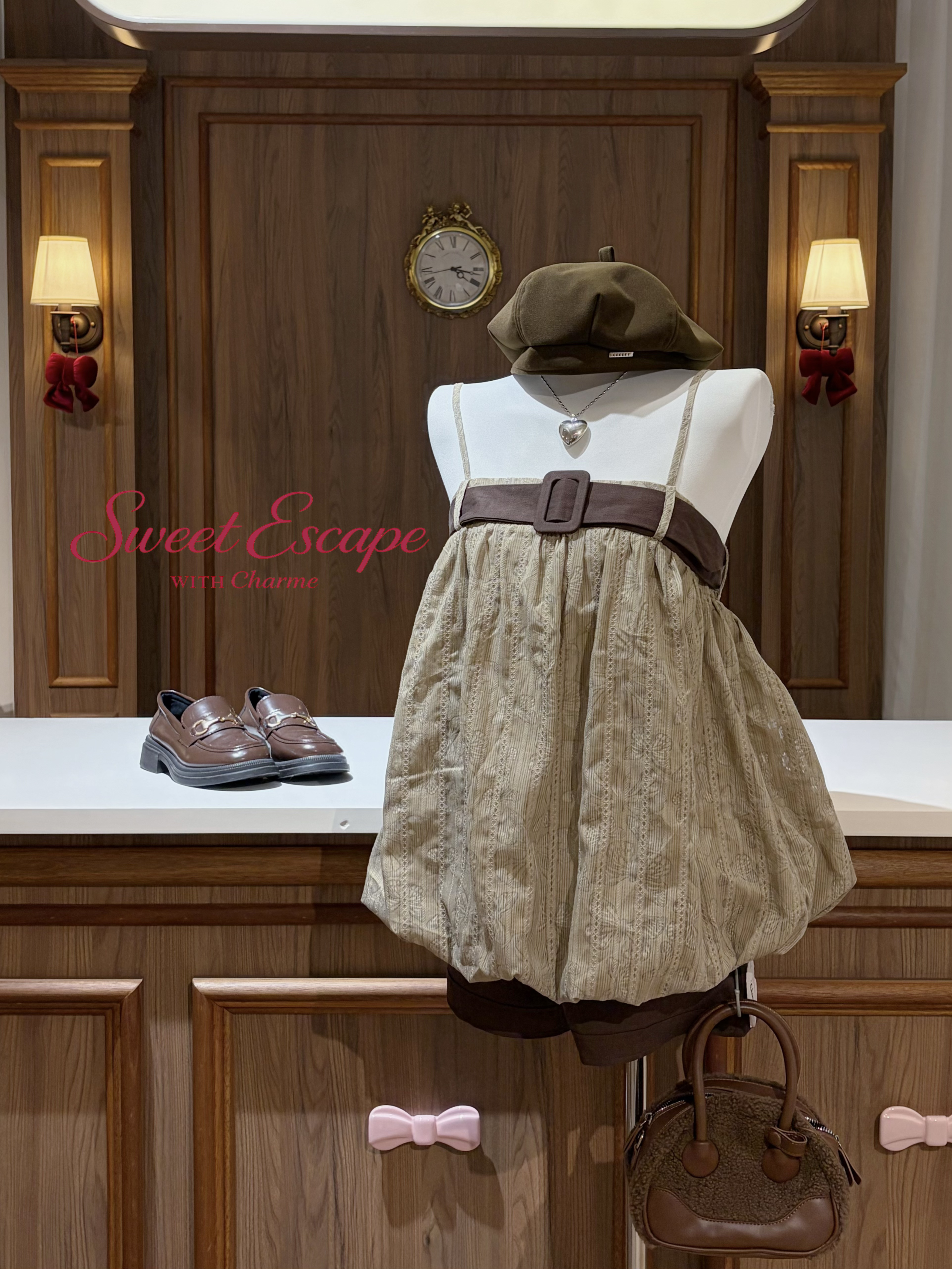 Mannequin wearing a beige dress with a brown belt, shoes, and handbag on a wooden background with 'Sweet Escape' branding.