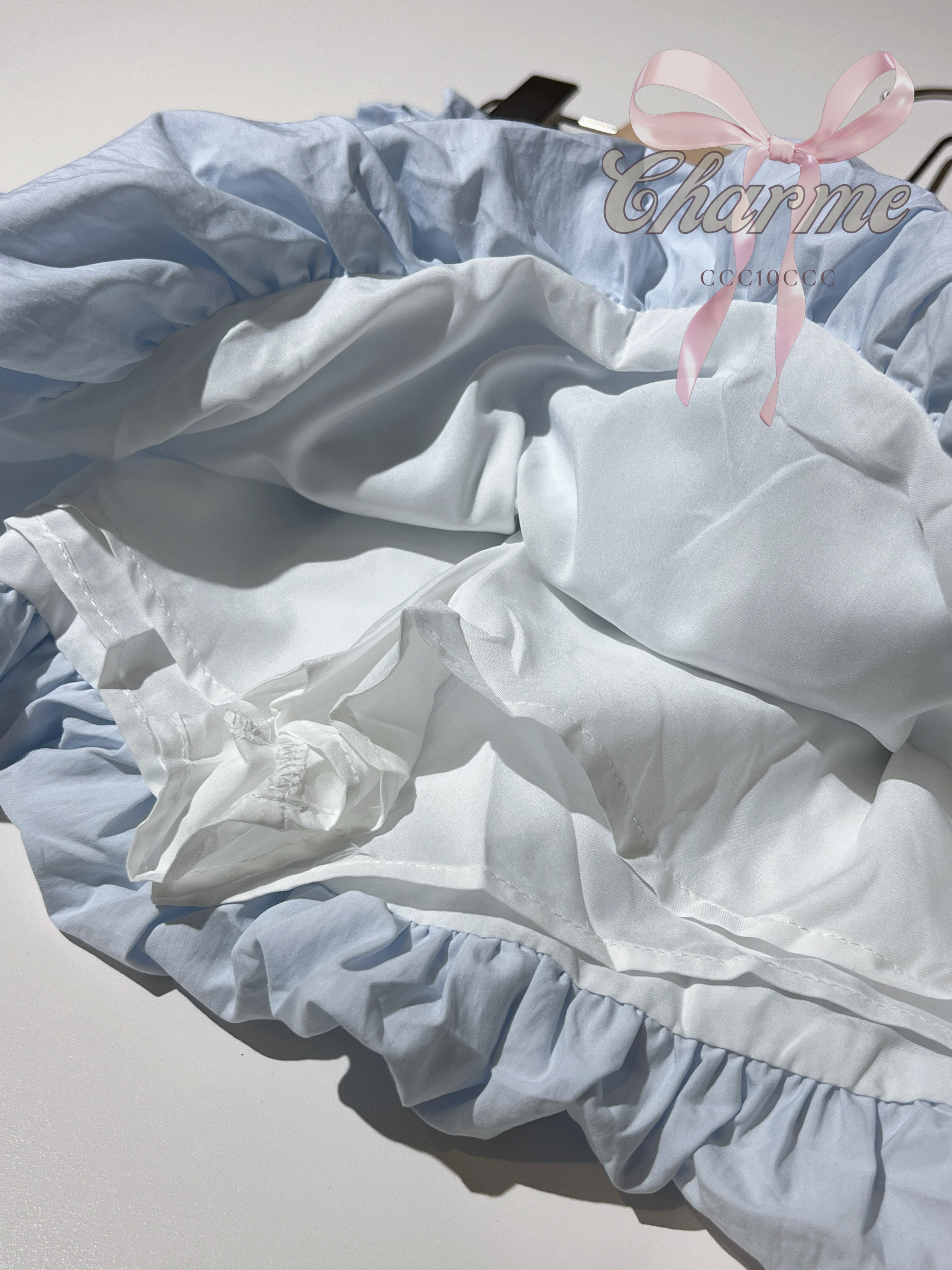 Light blue and white pet bed with ruffles and a pink bow on a white background.