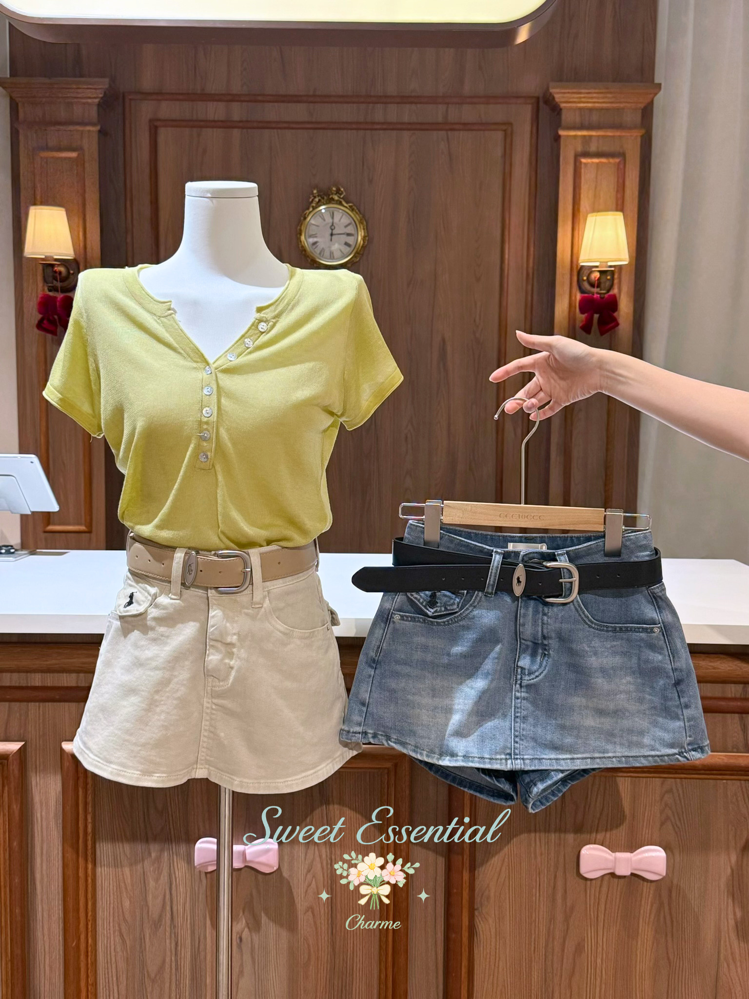Mannequin wearing a yellow top and beige shorts with denim shorts and black belt on a wooden background.