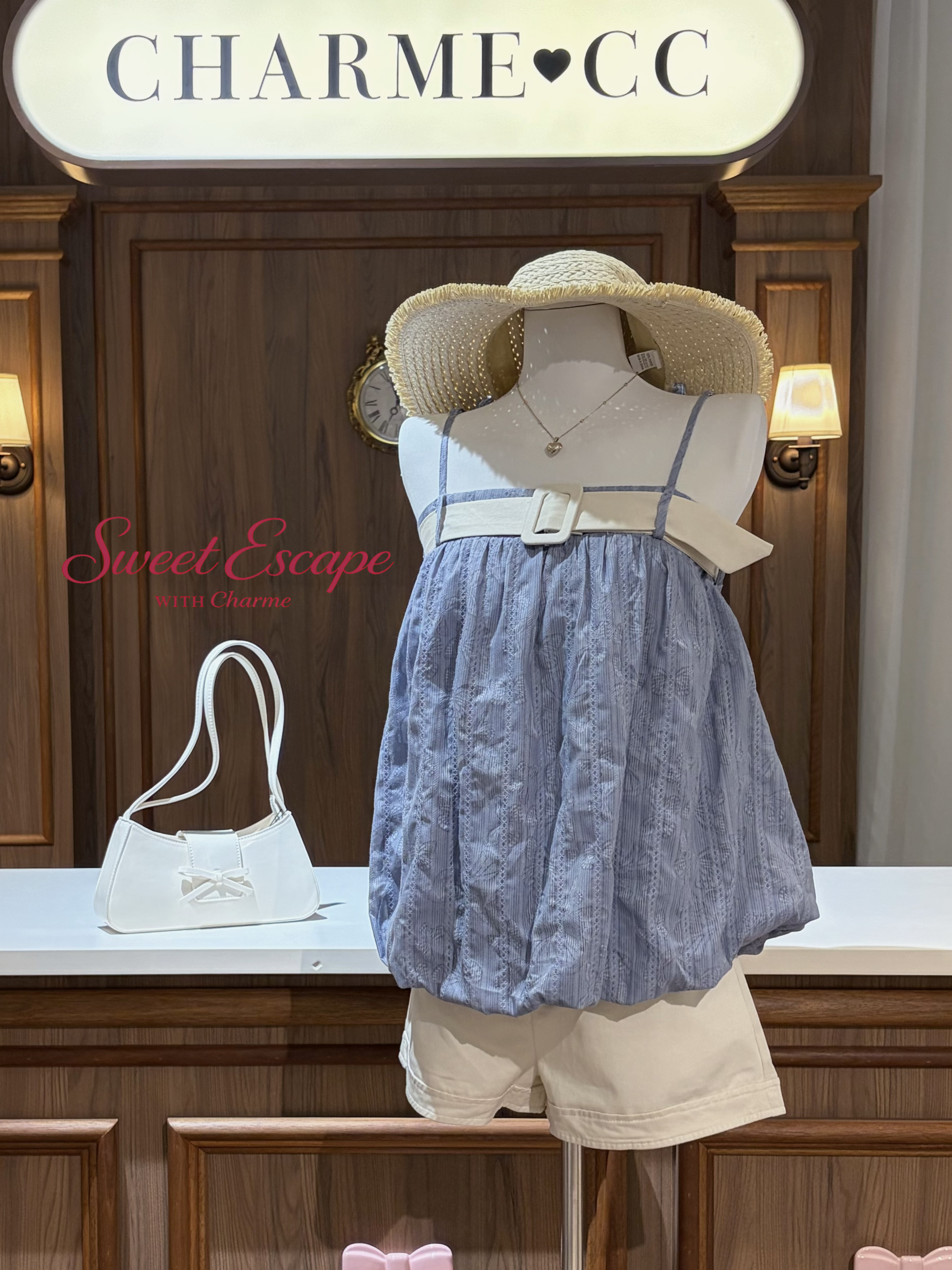 Mannequin wearing a blue dress and beige hat with 'Charme CC' branding in the background.