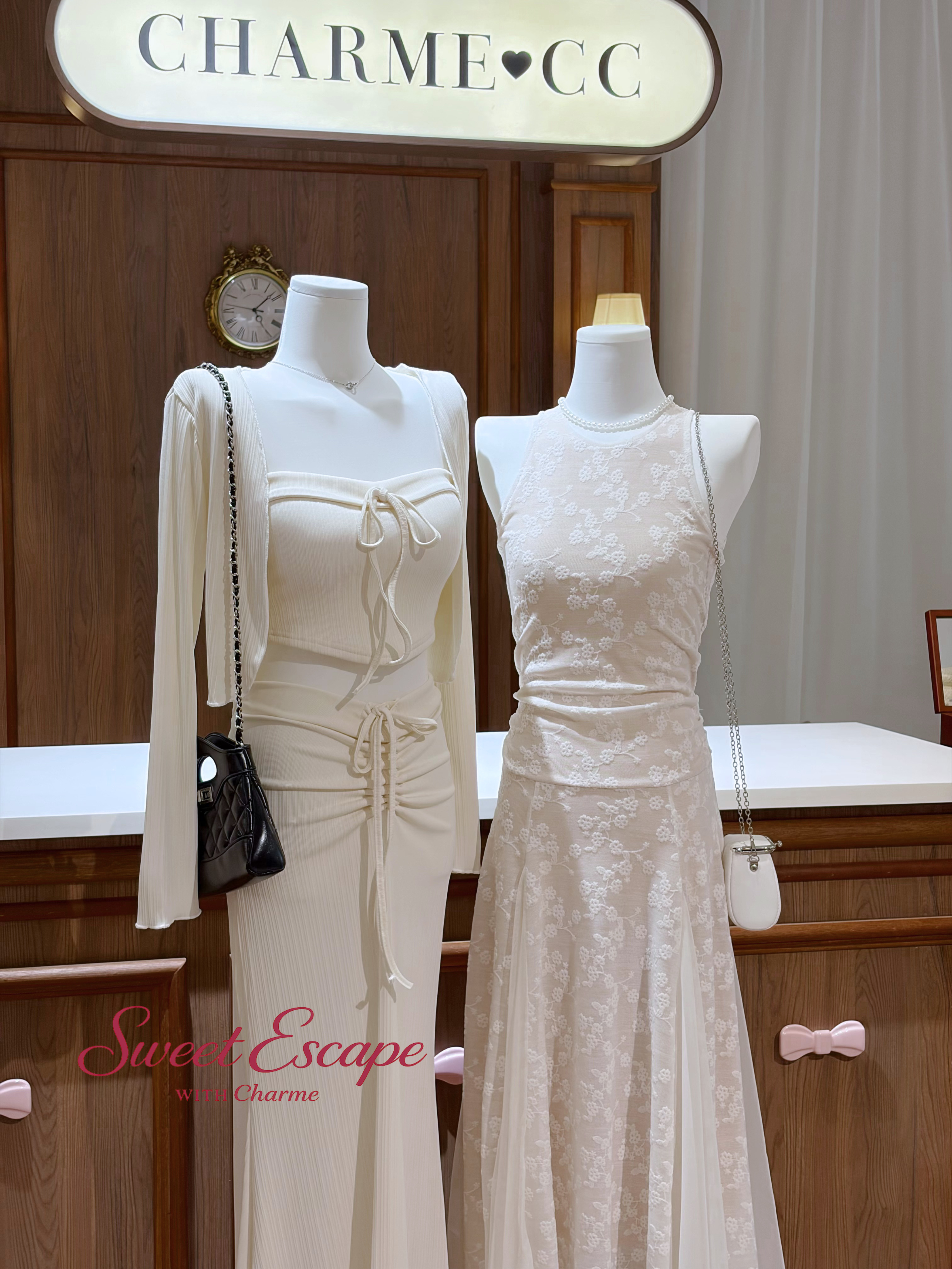 Two white dresses on mannequins with a 'Sweet Escape' sign in the background.