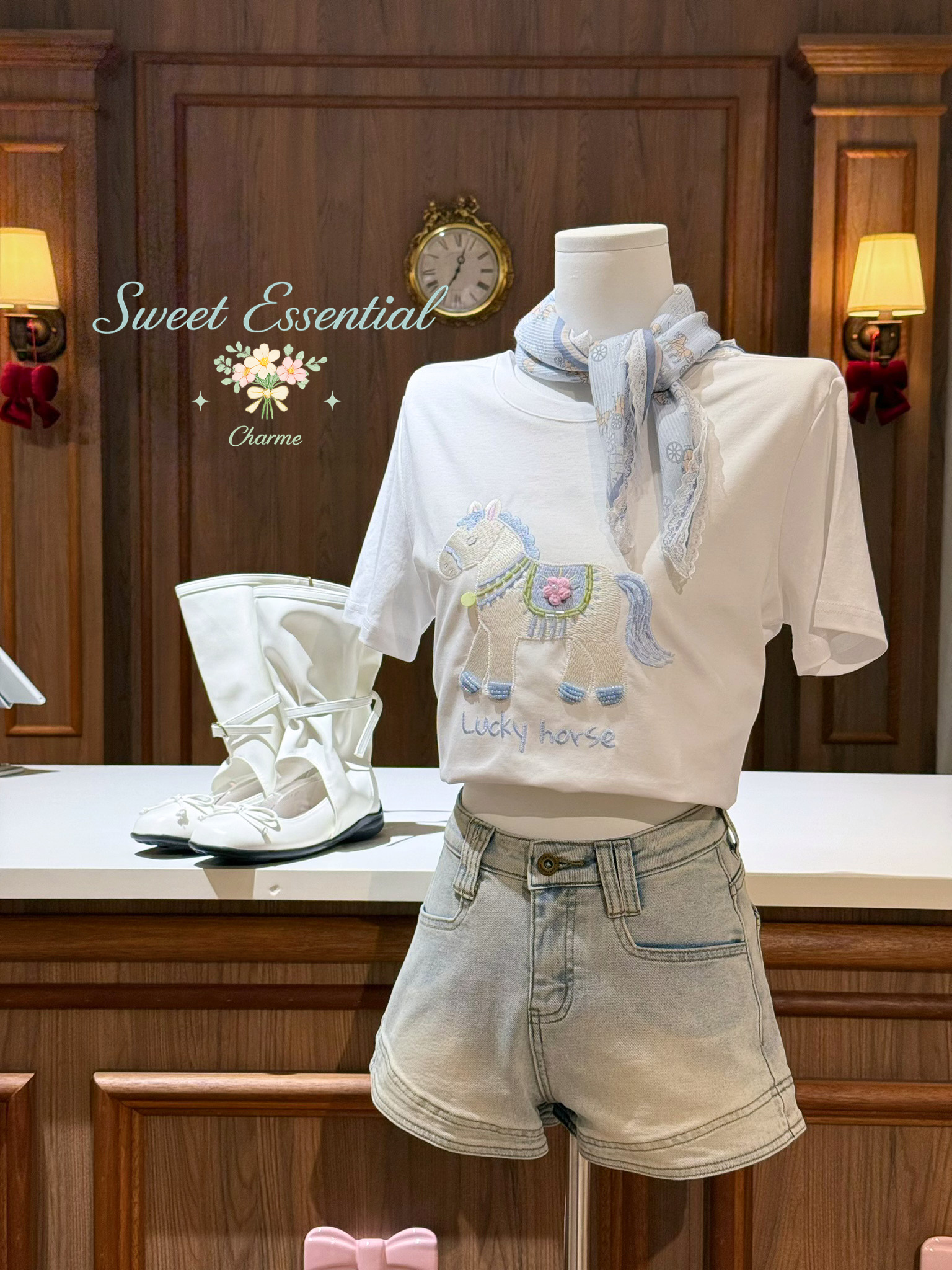 Mannequin wearing a white shirt with embroidery and denim shorts in a decorative setting.