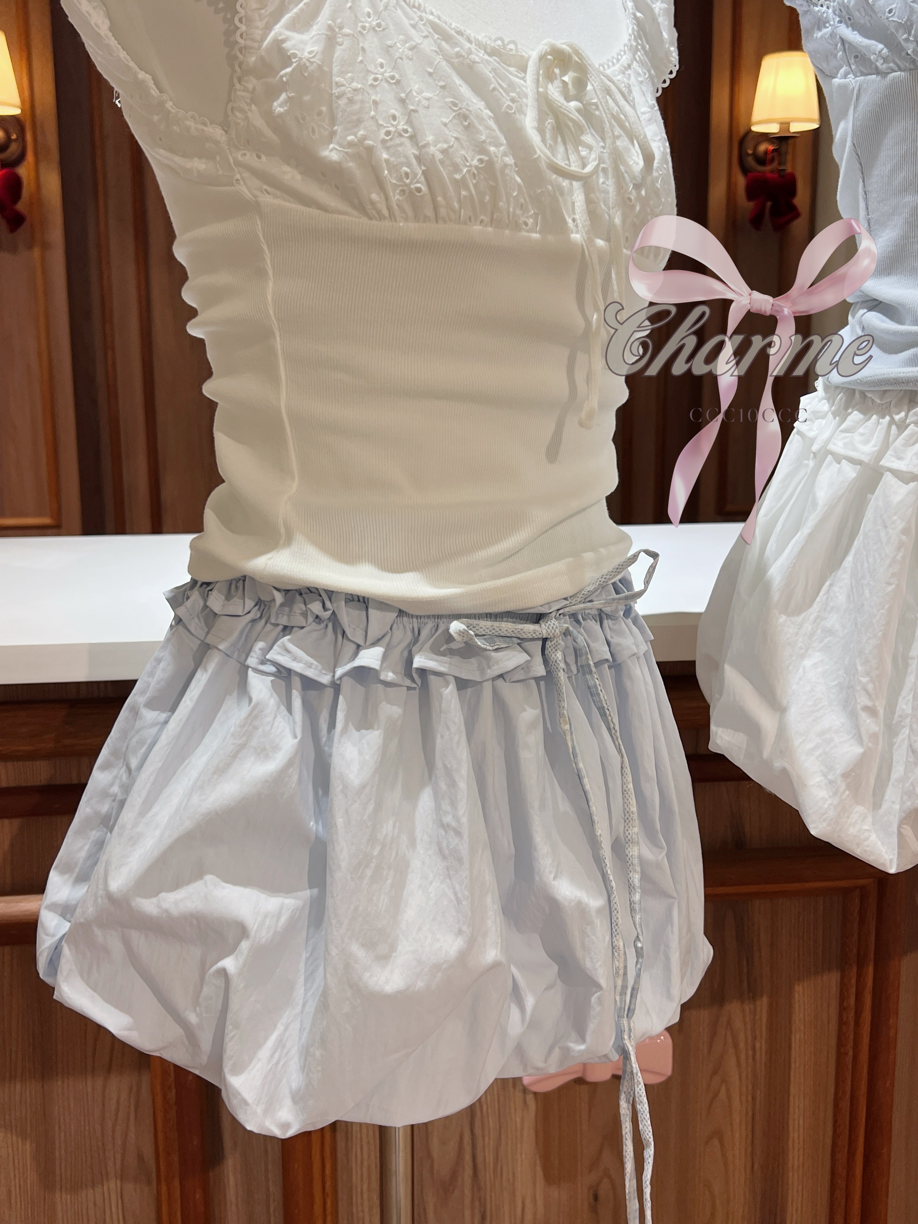 White lace top with a ruffled white skirt in front of a mirror.