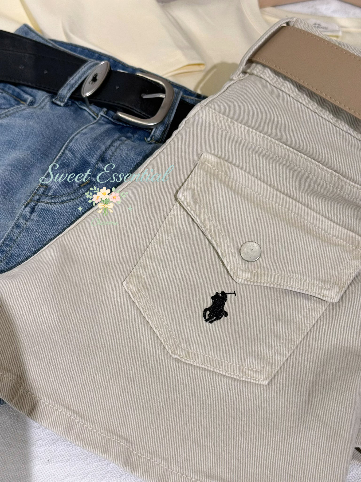 Beige pants with a brand logo on the pocket, featuring a black belt.