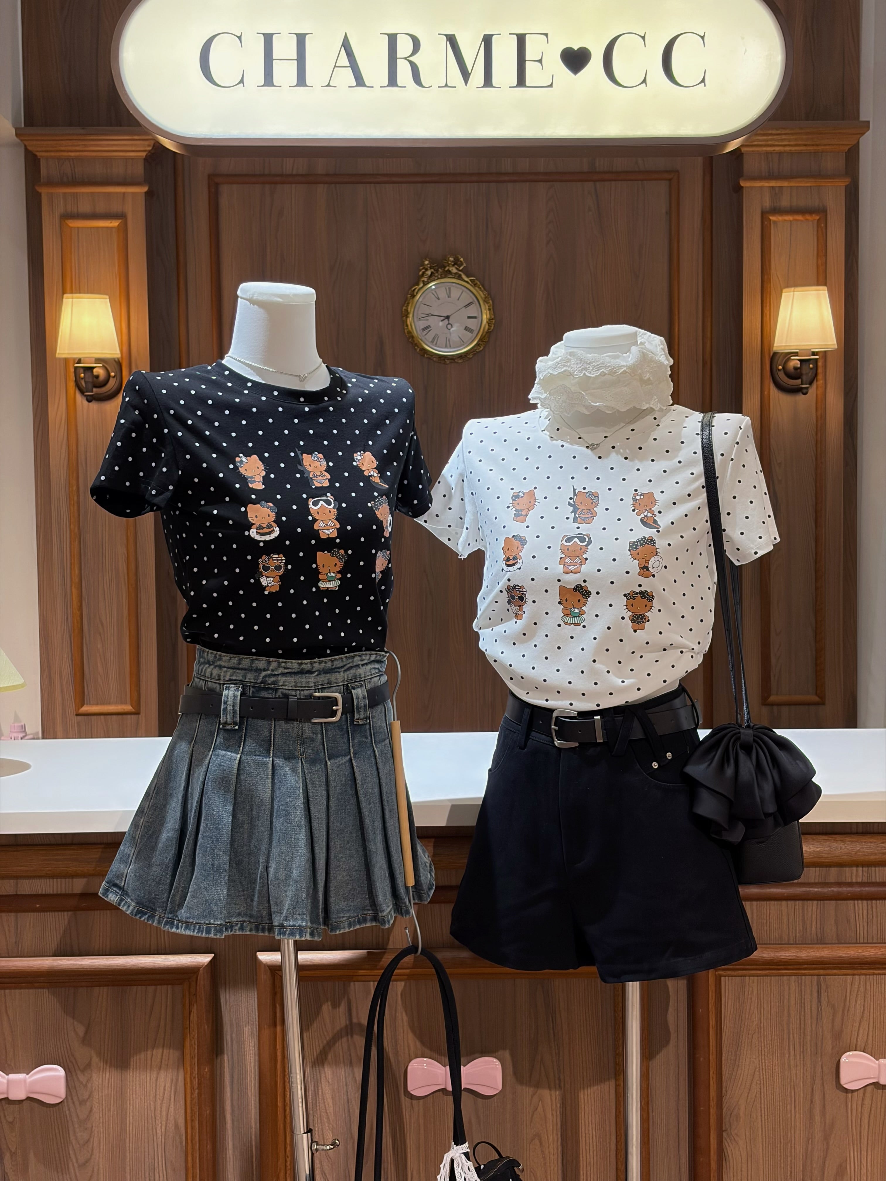 Two mannequins dressed in black and white tops with graphic designs, denim skirt, and black shorts in a store setting.